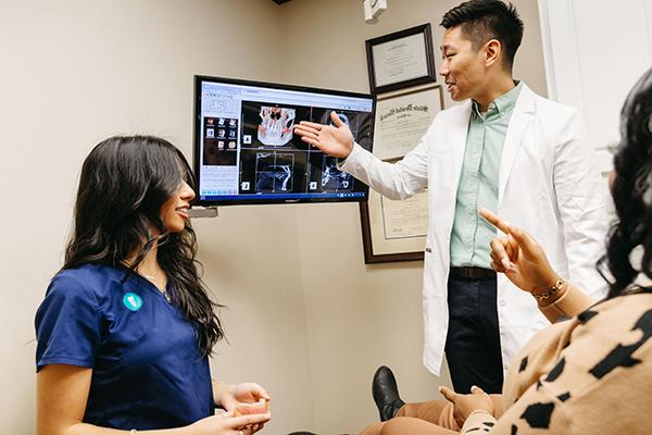 杰克逊维尔大学 Implantology resident discussing procedural options with a patient and a female chair-side assistant